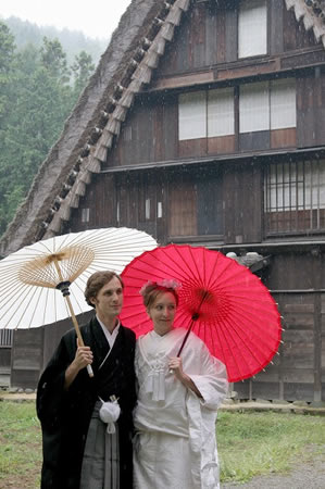 飛騨の里で雨の中和傘を指す外国人の新郎新婦