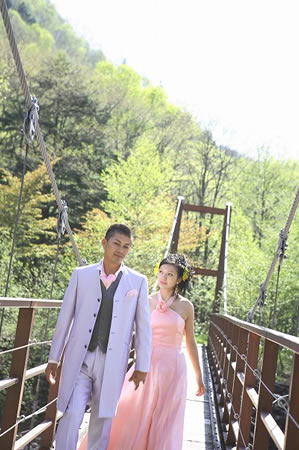 森の中のつり橋を渡る新郎新婦