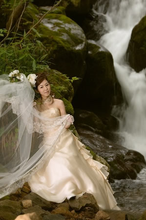 流れる滝の横でウェディングドレスを着た花嫁