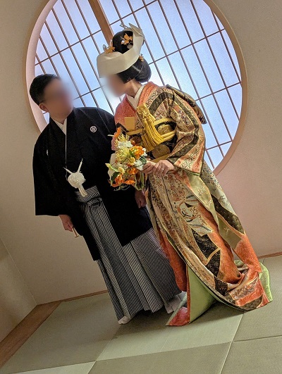 オレンジ色のリメイク引き振袖を着た花嫁と花婿